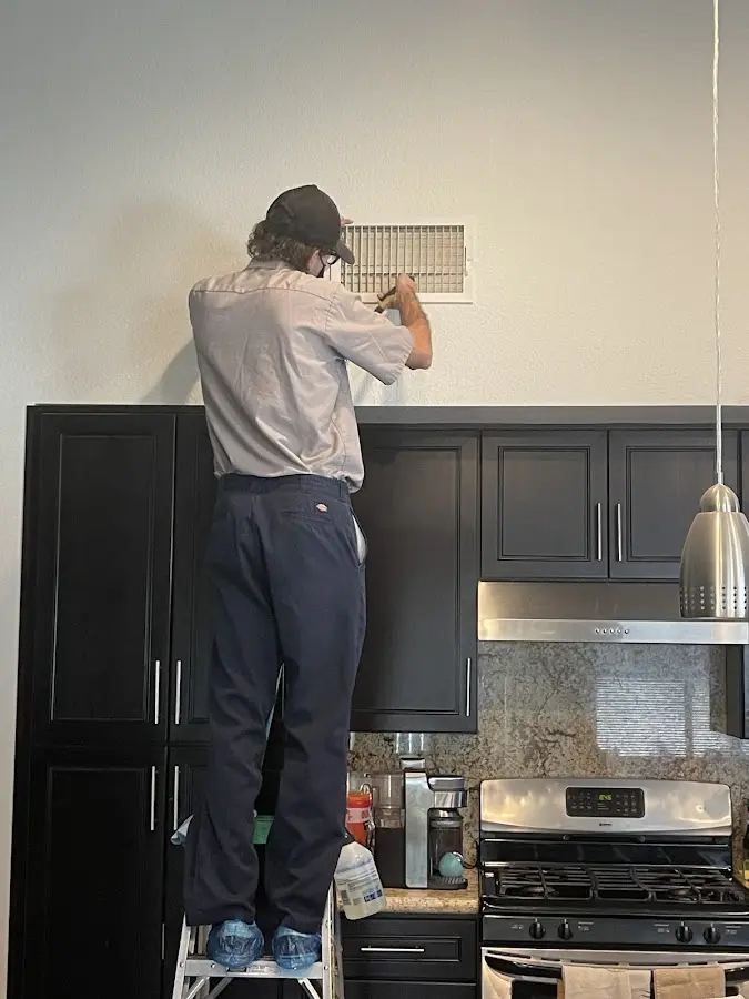 Technician inspecting an air vent during HVAC service in Grand Forks